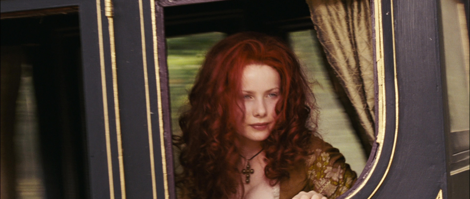 a woman with red hair looking out of a train window