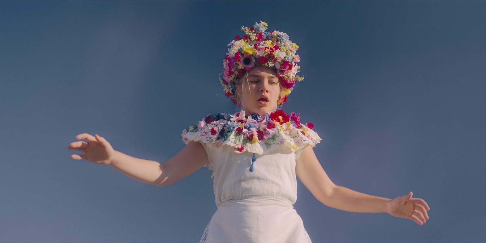 a young girl wearing a white dress and a flower crown