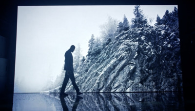 a man is walking in front of a picture of a mountain