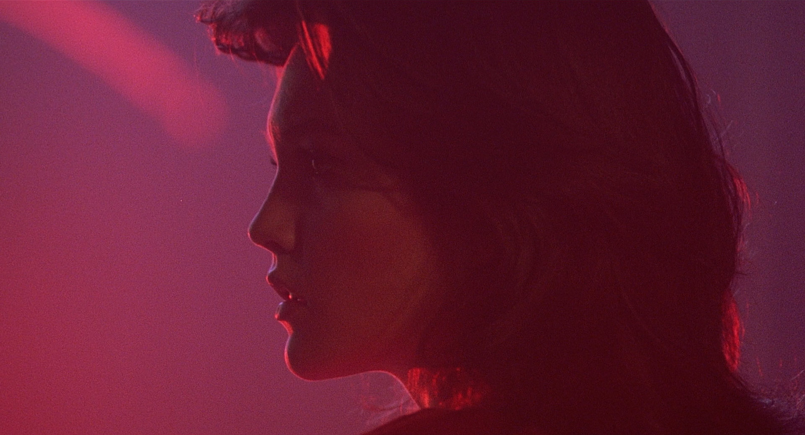 a close up of a woman's face with a red light in the background