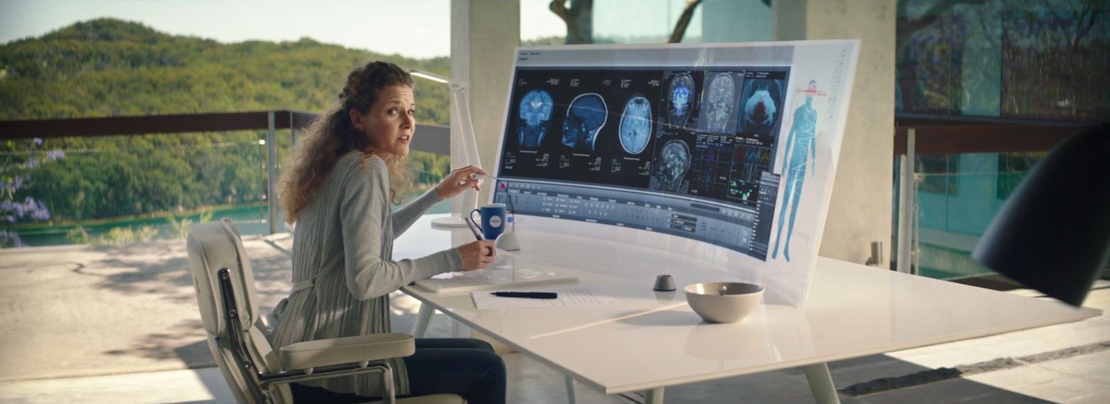 a woman sitting at a table in front of a computer screen