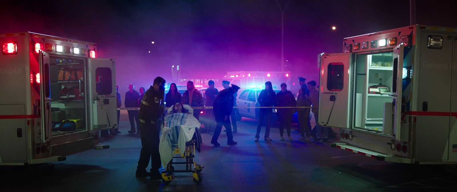 a group of people standing next to ambulances at night