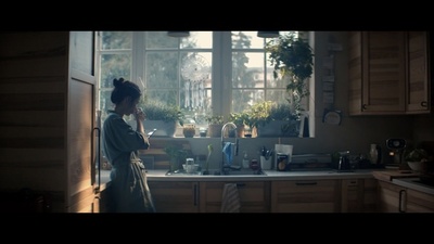 a woman standing in a kitchen talking on a cell phone