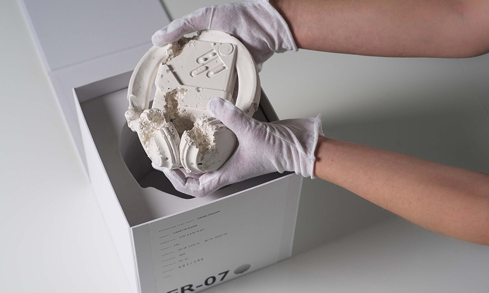 a person in white gloves holding a white object in a box