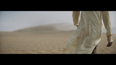 a man walking across a desert covered in sand