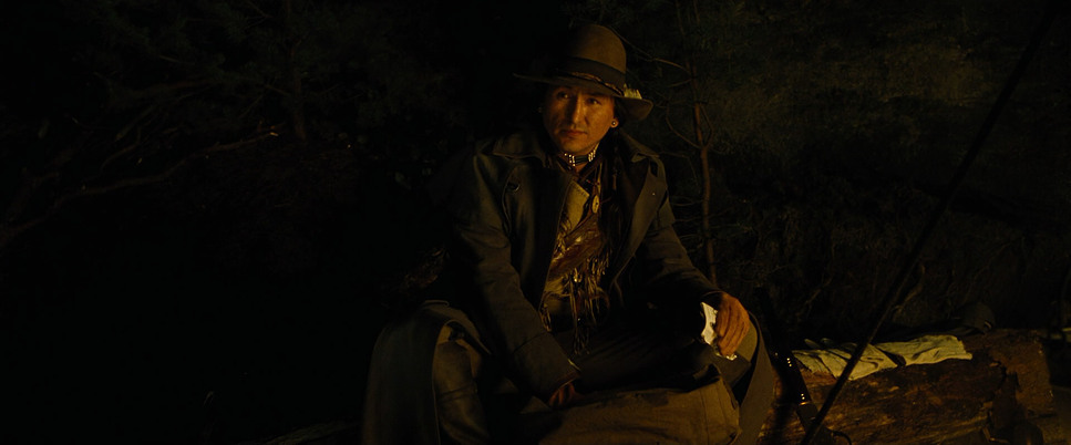 a man in a hat is sitting in the dark