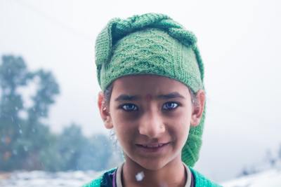 a young girl wearing a green knitted hat