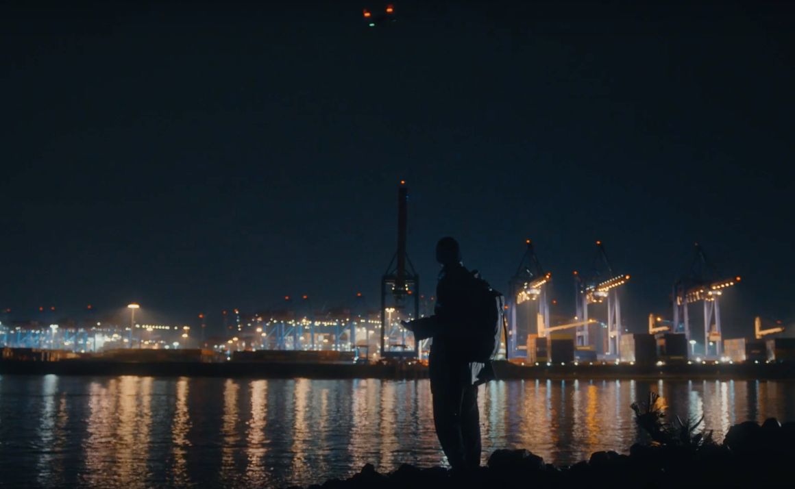 a man standing in front of a body of water at night