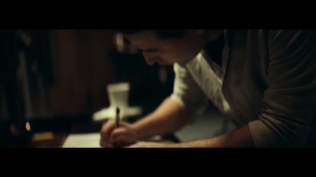 a man sitting at a desk writing on a piece of paper