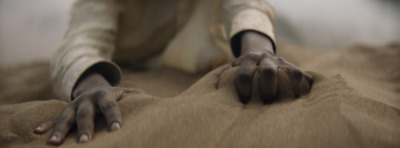 a person laying on the ground with their hands in the sand