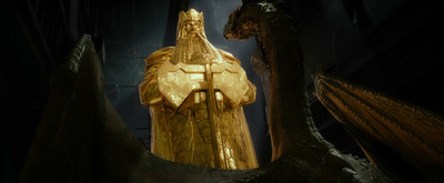 a golden statue of a man standing in front of a dragon