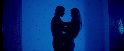 a man and a woman standing in front of a blue wall