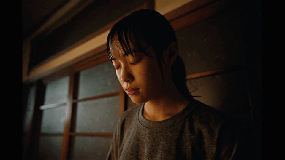 a girl in a gray shirt is standing in a dark room