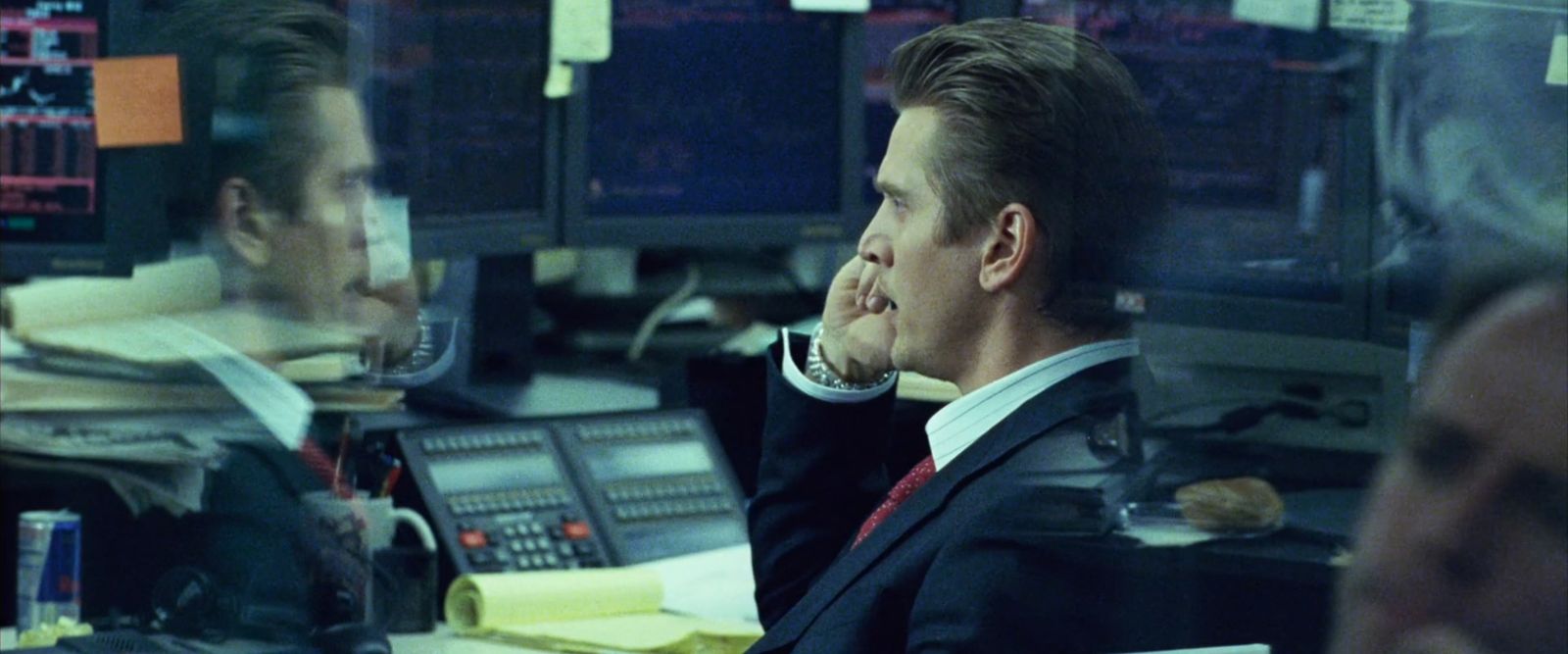 a man in a suit sitting in front of a computer monitor