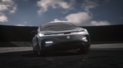 a futuristic car driving on a road under a cloudy sky