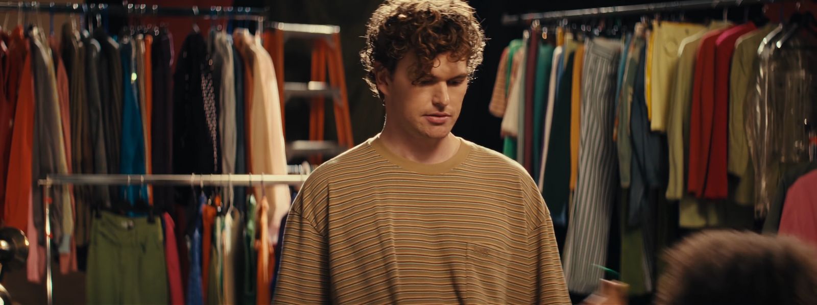 a man standing in front of a rack of shirts