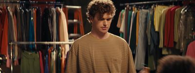 a man standing in front of a rack of shirts