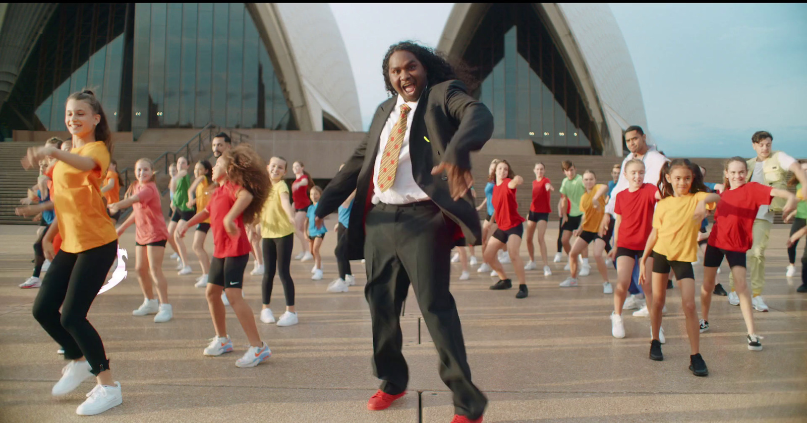 a man in a suit and tie dancing in front of a group of children