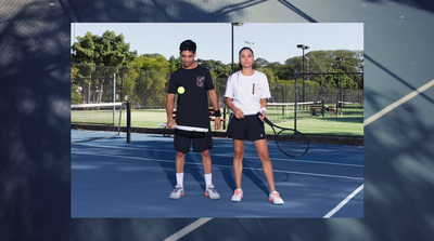 a man and woman standing on a tennis court holding racquets