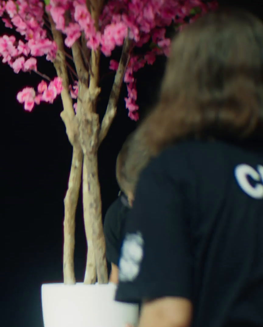 a woman holding a cup in front of a pink tree