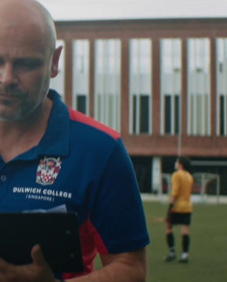 a man standing on a soccer field holding a clipboard