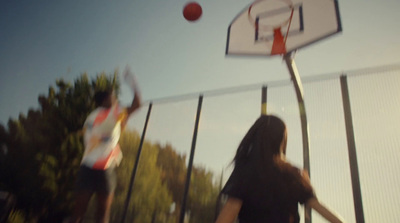 a man and a woman playing basketball in a fenced in area