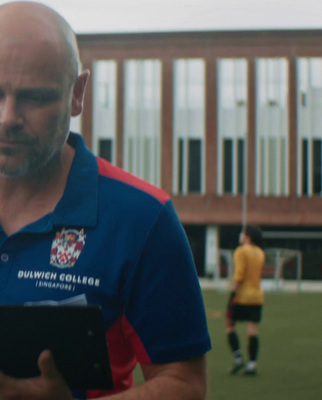 a man holding a tablet in front of a soccer field