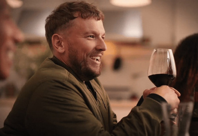 a man sitting at a table with a glass of wine