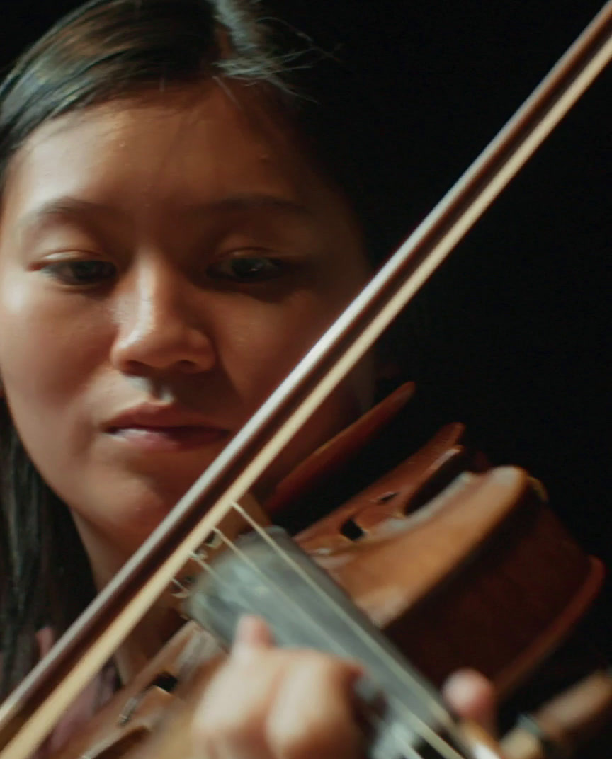 a woman playing a violin in a dark room