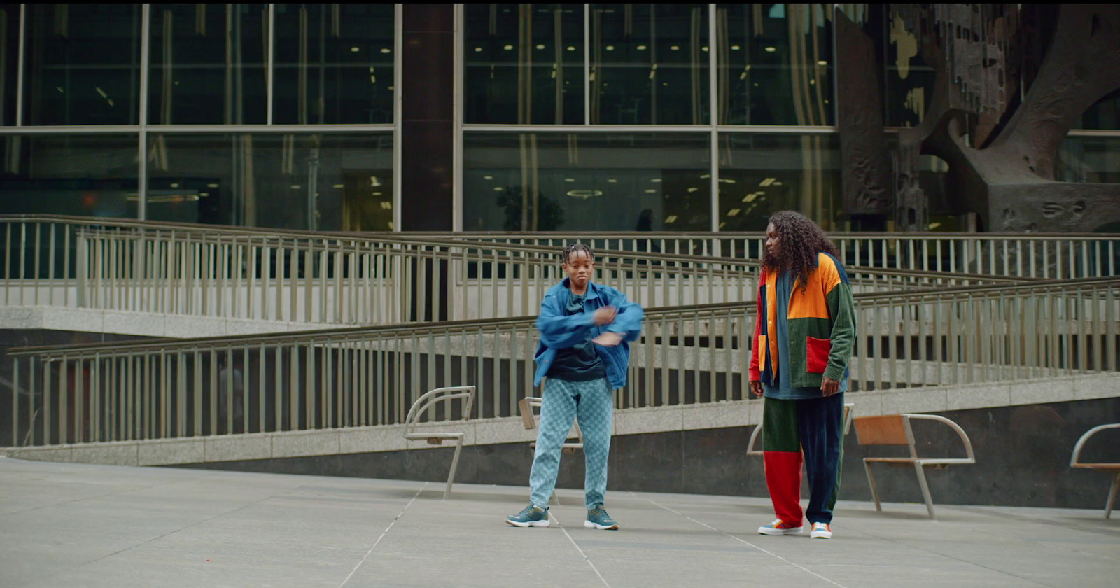 two people standing in front of a building talking on a cell phone