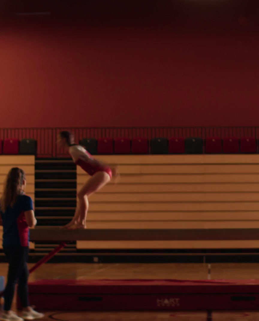 a girl doing a handstand on a beam in a gym