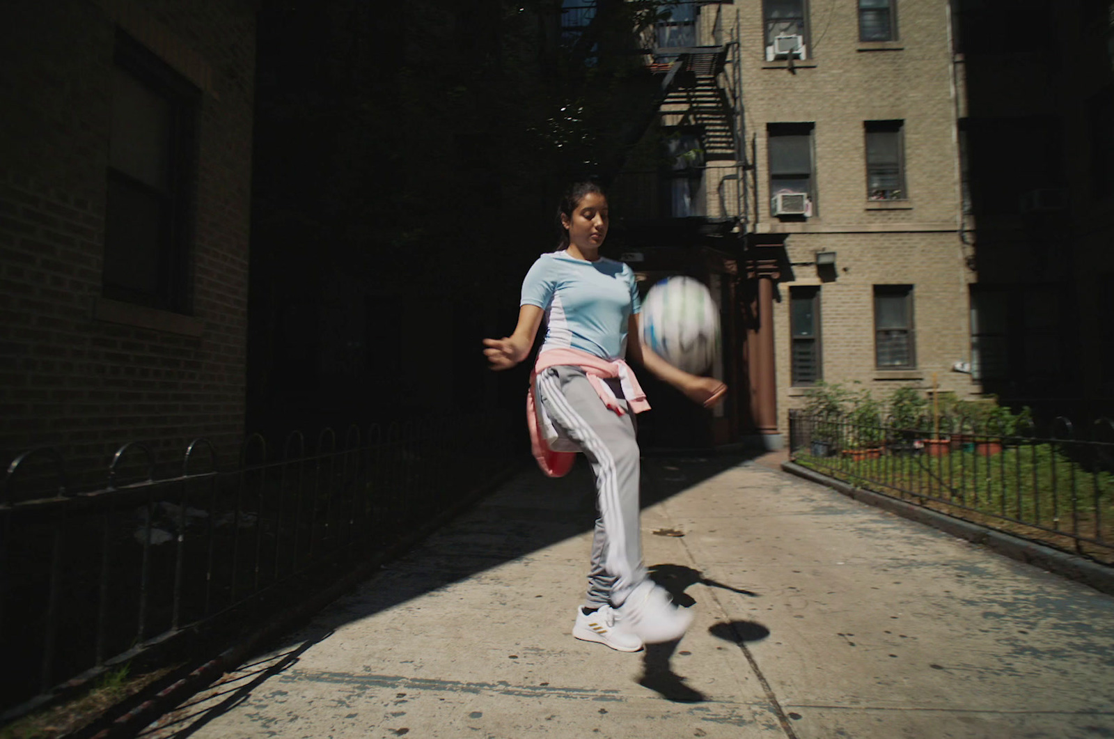 a woman kicking a soccer ball on a city street