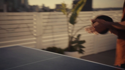 a man is playing ping pong on a rooftop