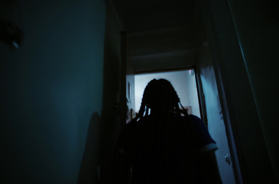 a person with dreadlocks standing in a dark hallway