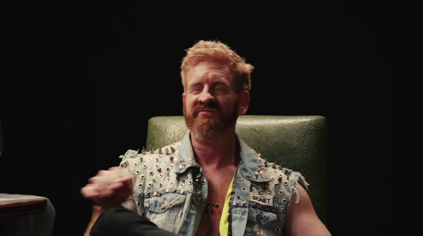 a man sitting in a green chair with a yellow shirt on