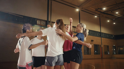 a group of young women standing on top of a basketball court