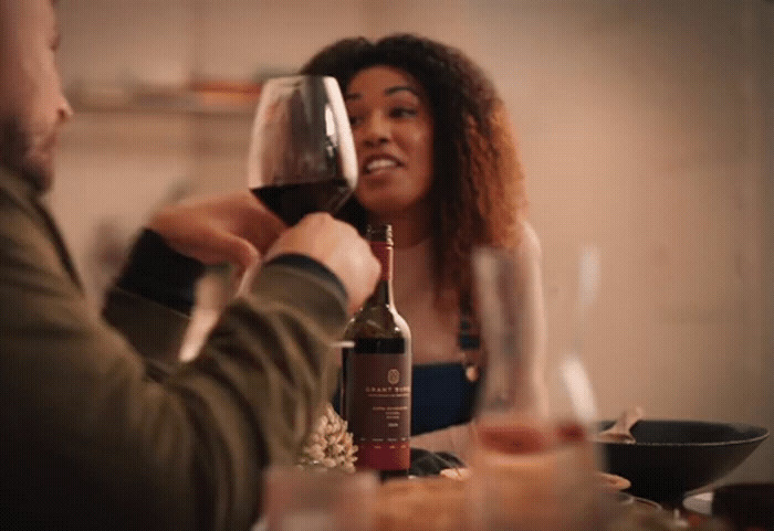 a man and a woman sitting at a table drinking wine