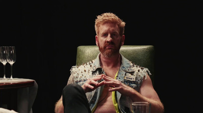 a man sitting in a chair with a glass of wine