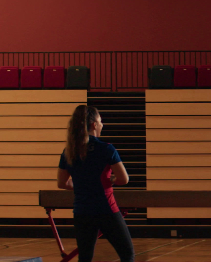 a woman holding a bench in a gym