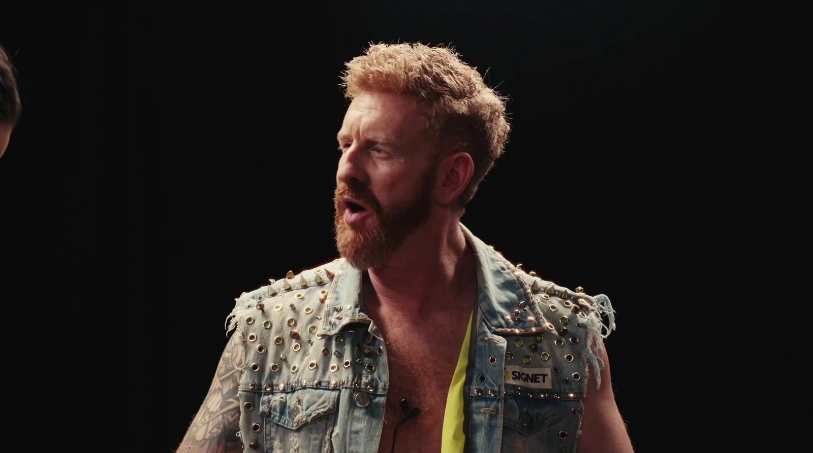 a man with a beard wearing a denim vest