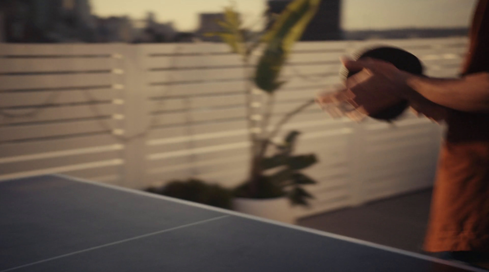 a man is playing ping pong on a rooftop