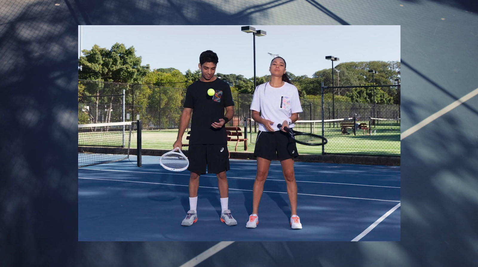 a couple of people standing on a tennis court holding racquets