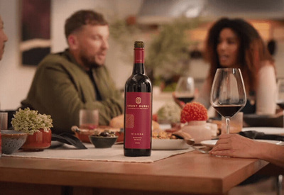 a group of people sitting around a table with a bottle of wine