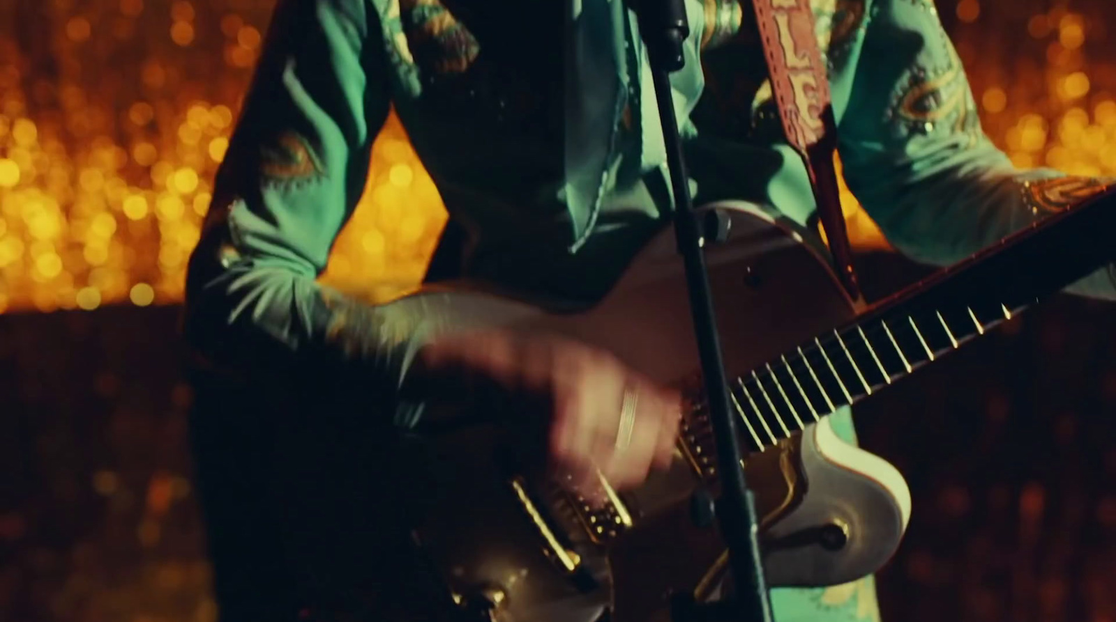 a man playing a guitar in front of a microphone