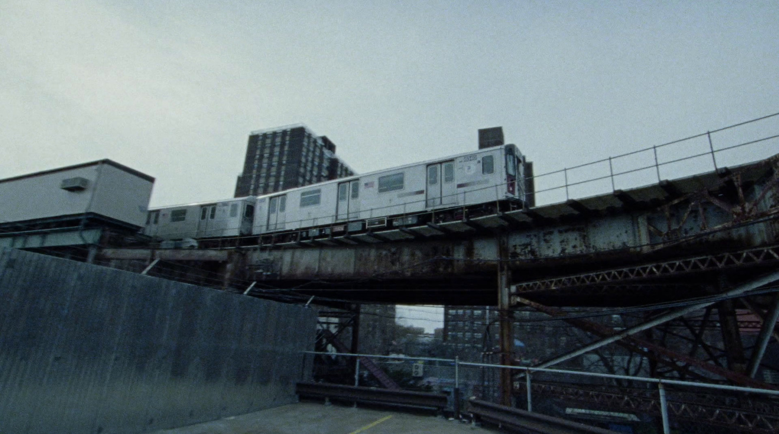 a train traveling over a bridge with tall buildings in the background