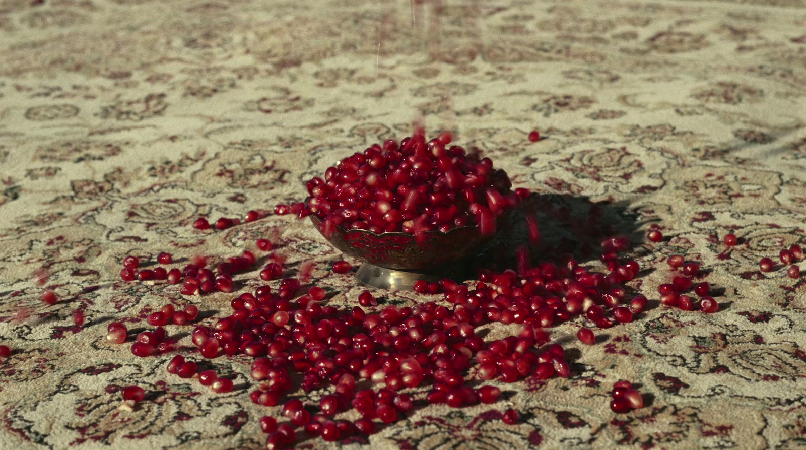 a bowl filled with red berries sitting on top of a rug