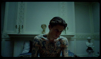 a man with tattoos sitting on a bed