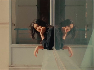 a woman sitting on a window sill talking on a cell phone