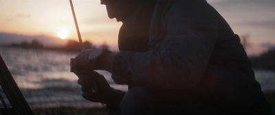 a man holding a cell phone while standing next to a fence