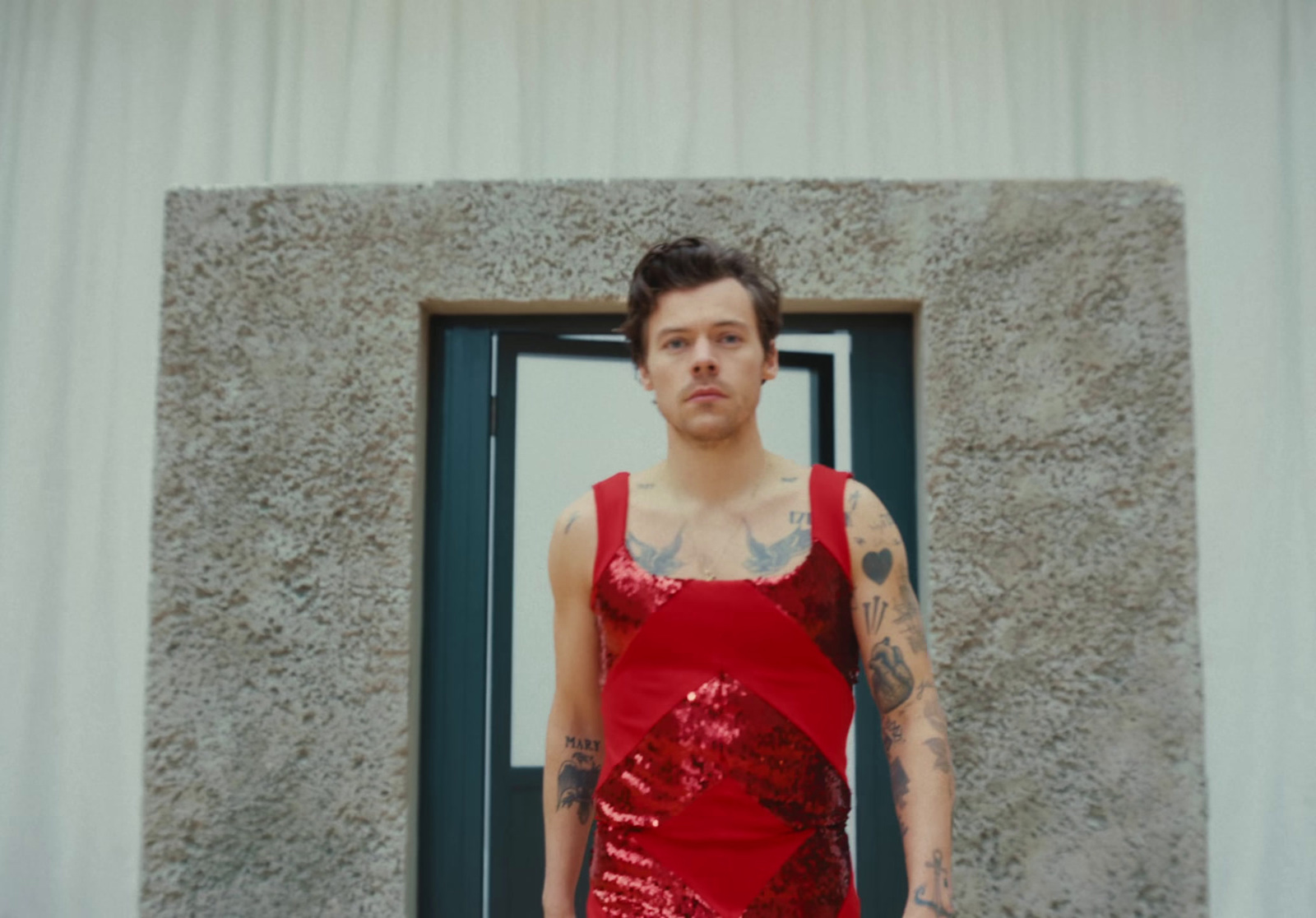 a man in a red dress standing in front of a door